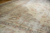 Worn texture of a vintage Sparta carpet showing muted ivory, beige, and subtle rose floral design.
