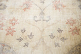 Worn pile with visible foundation, featuring faded floral vinery in pale rose and charcoal.
