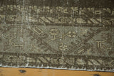 Distressed geometric floral pattern in charcoal, gray, and beige tones with secured fringe.