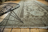 Distressed Kula runner corner, featuring geometric floral interpretations in gray, beige, and soft ivory fringe.