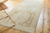 Vintage distressed Oushak rug runner showing an oversize geometric medallion, border, and fringe.