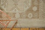 Distressed low pile texture, beige geometric patterns, and fringe on a vintage Oushak rug.
