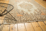 Distressed vintage Oushak rug corner showcasing rectilinear spandrels and fringe.