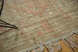Distressed Tulu rug with blush and beige low pile, visible foundation, and tattered fringe.