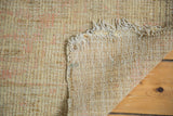 Underside of a vintage distressed Tulu rug, revealing woven foundation and frayed fringe.