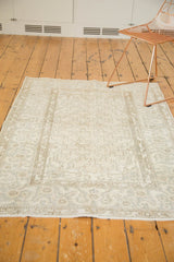 Distressed pale beige Oushak rug, showing soft pile, subtle pattern, and fringe.