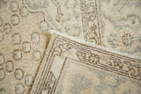 Pale beige distressed Oushak rug shows low pile, hand-knotted reverse, and fringe detail.