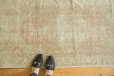 Distressed Oushak rug with even wear, foundation showing, in faded blush and ivory hues.