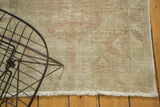 Distressed vintage Oushak rug's worn pile showcasing soft blush and ivory fringe.