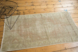 Distressed vintage Oushak rug corner with faded blush, ivory, and textured wear.
