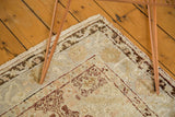 Vintage Oushak rug corner, showing delicate floral motifs in faded gold and wine red.