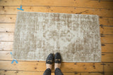 Oushak rug corner highlighting distressed ivory, soft brown tones, visible foundation, blanket-stitched edge.