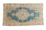 Distressed vintage Oushak rug featuring a sky blue field, beige floral medallion, and Rococo spandrels.