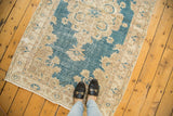 Detail of the distressed sky blue field with beige stylized Rococo floral patterns.