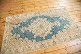 Distressed Oushak rug's pale sky blue field, showing beige floral motifs and visible foundation.