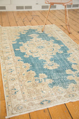 Distressed sky blue and pale sand Oushak rug corner with Rococo spandrel detail.