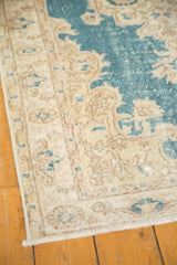 Corner of distressed vintage Oushak rug, featuring Rococo spandrels in sky blue and beige.
