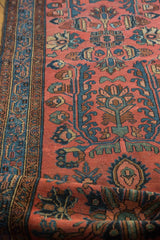 Rolled vintage Lilihan runner showcasing indigo border and madder red field with blossoming floral motifs.