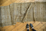 Distressed vintage Malayer runner showing muted bronze, moss tones and visible foundation.