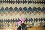 Artfully distressed Dosmealti rug: geometric diamond lattice in muted navy, teal, and blush.