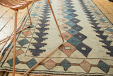 Distressed Dosmealti rug's geometric diamond patterns in ivory, navy, and rose with worn texture.