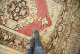Distressed Oushak carpet displaying its oversized top niche and faded cherry red field.
