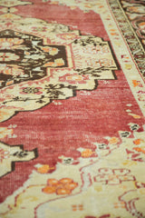 Distressed vintage Oushak rug with worn cherry red pile and antique ivory patterns.