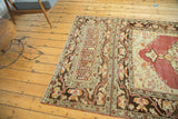 Distressed vintage Oushak rug corner with complex floral border in faded cherry, brown, ivory.