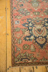 Distressed vintage Hamadan runner corner showing blush field, navy floral motifs, vine border, and pile wear.
