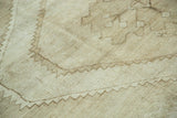 Faded geometric zigzag pattern in neutral beige and light brown on a distressed Oushak pile.