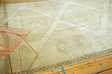 Distressed texture and narrow vine motif border on this vintage Oushak carpet.