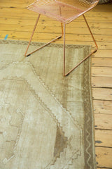 Vintage distressed Oushak carpet corner with geometric patterns and worn neutral tones.