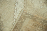 Distressed vintage Oushak rug, showing even wear on neutral pile and hand-knotted selvage.