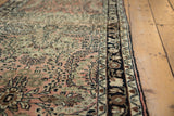 Vintage Lilihan rug runner's even pile with repeating dusty rose floral sprays and dark border.