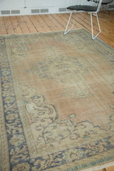 Angled view of distressed Oushak carpet, highlighting softened apricot pile and ink blue border.