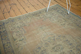 Faded apricot and blue distressed texture of a vintage Oushak carpet corner.