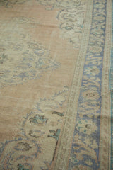 Distressed vintage Oushak rug pile featuring faded apricot and pale blue designs.
