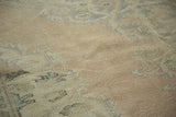 The worn, low pile of the distressed vintage Oushak carpet in soft apricot and faded blue.