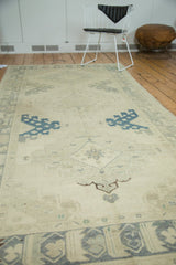 Decorative distressed Oushak runner with muted ivory, slate blue, and beige medallion patterns.