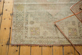 Distressed Oushak rug corner with geometric border and blush, beige, and silver tones.