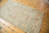 Distressed vintage Oushak rug corner showing faded pastel geometric patterns and aged texture.