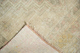 Distressed Oushak rug corner reveals hand knotted foundation and subtly faded colors.