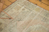Vintage distressed Oushak rug with faded blush, dusty gold geometric motifs and soft texture.