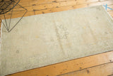 Faded pale silver and saffron highlights accenting the distressed Oushak runner's corner spandrel.
