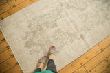 Distressed Oushak runner with faded sea foam green and pale blush floral motifs.