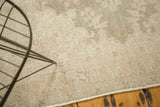 Corner of distressed Oushak rug runner, showing faded pale patterns and even wear.