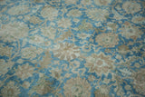 Distressed pile texture of Tabriz rug, showing pale blue and dusty gold palmettes and vinery.