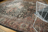 Distressed Mahal carpet corner, featuring worn madder red, black, and ivory border designs.