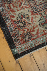 Distressed corner of Persian Mahal rug; madder red, charcoal, sea foam patterns, exposed foundation.
