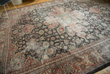 Distressed vintage Mahal carpet with charcoal field, red floral vinery, and aged silver accents.